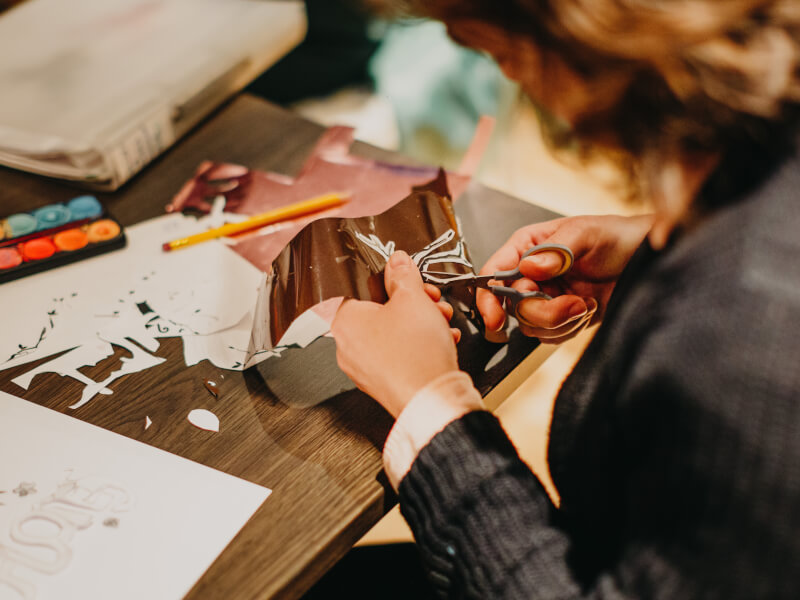 A person cuts shapes out of paper in a craft class.